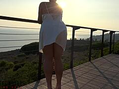 Rijpe vrouw in witte jurk heeft buitenseks op het balkon