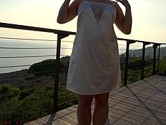 Зрела жена у белој хаљини има секс на отвореном на балкону