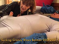 A mature woman performs fellatio on a superhero