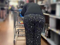 큰 엉덩이를 가진 구부러진 엄마가 월마트에서 쇼핑을 합니다